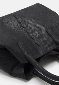 Svart handväska med textur och sandad finish, två robusta handtag och rektangulär form. Har minimalistiska designelement.