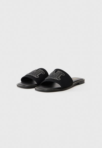 Svart slide-sandaler med en teksturert stoffrem som har en fremtredende logo, flat såle og kontrasterende sømmer.