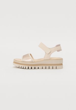 Beige platform sandalen met een metallic gouden band, verstelbare klittenbandsluiting en een getextureerde zool met ribbels voor grip.