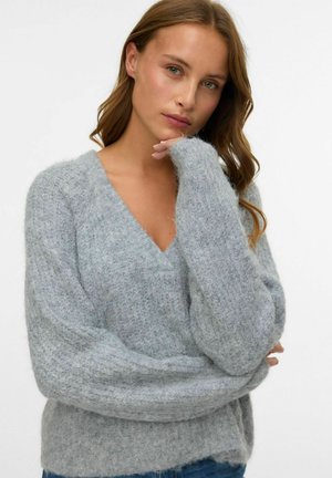 Grå strikket sweater med V-hals, oversized pasform og lange ærmer. Materialet ser blødt og tekstureret ud, med et hyggeligt look.