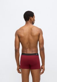 Maroon boxershorts gemaakt van soepel stof, met een zwarte tailleband met logodetail. Het ontwerp is aansluitend met een midilange snit.