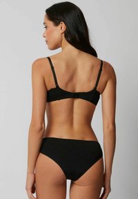Zwarte bh en bijpassende bikini-slip, met kantdetails op de bh en een gladde textuur. Verstelbare bandjes en een haaksluiting.