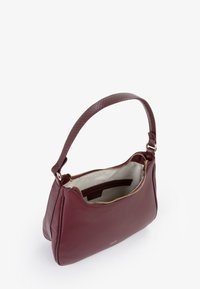 Borsa in pelle bordeaux con tracolla strutturata, corpo liscio, zipper dorata e interno color crema, dotata di una tasca piccola.