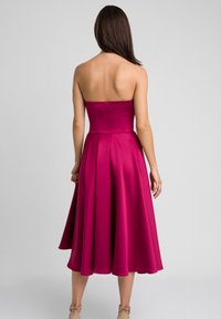 Bezramienna sukienka w fuksjowym kolorze z dopasowanym gorsetem i rozkloszowanym dołem. Gładka satynowa faktura, długość do kolan, z tylnym zapięciem na zamek.