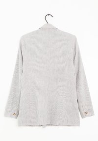 Jasnoszary żakiet w prążki wiszący na czarnym wieszaku, wyeksponowany od tyłu, z długimi rękawami i detalami w postaci guzików na mankietach.