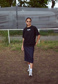 Black oversized t-shirt with "ENGLAND" and Nike logo, paired with a denim midi skirt and white sneakers with red accents.