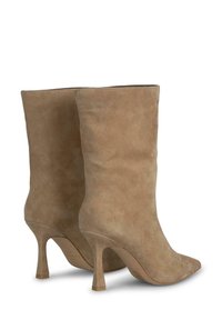 Bottines en daim beige avec un bout pointu et un talon aiguille de 7,5 cm. Texture lisse, forme ajustée, détails minimaux.