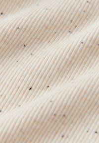 Neutralfarbener, gerippter Stoff mit dezenten Sprenkeln; verfügt über eine weiche, strukturierte Oberfläche und vertikale Streifen für ein gemütliches Aussehen.