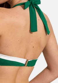 Groen en witte bikini-top met geweven textuur, halternekontwerp en een gouden sluiting aan de achterkant. Bindt zich om de nek met een groene lint.