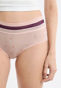 Różowe majtki w paski z szerokim fioletowym pasem, ozdobione wzorem kieliszków koktajlowych i wiśni, wykonane z miękkiego materiału.