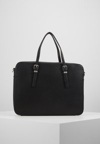 Bolso de cuero negro con un acabado texturizado, dos asas superiores y accesorios en plata. Forma rectangular con cierre de cremallera.
