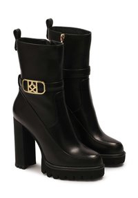 Black leather ankle boots with a high block heel. Features a gold buckle detail on the strap and a textured rubber sole for grip.