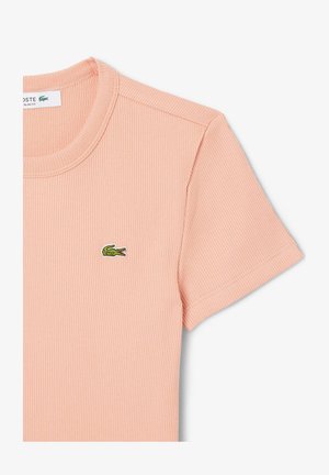 Kratkoročni rebrasti T-shirt v mehko breskvi z okroglim izrezom in majhnim zelenim logotipom krokodila Lacoste na prsih.