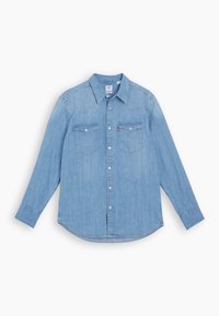 Chemise en denim bleu clair à manches longues avec fermeture à boutons, deux poches poitrine à rabats et col pointu sur fond blanc.