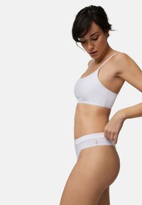 Bralette de algodón blanco con tirantes finos y braguitas de tiro alto a juego. Presenta una textura suave y un delicado borde de encaje en la cintura.