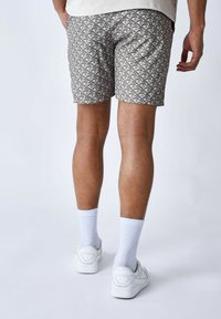 Pantalones cortos estampados para hombre en beige y gris, con un diseño geométrico. Fabricados con un material ligero, tienen un corte relajado y bolsillos laterales.