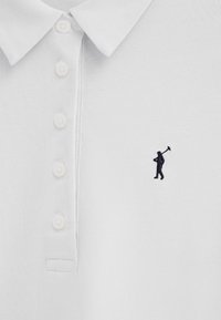 Polo blanc avec quatre boutons blancs et un petit logo brodé noir représentant une personne portant un club de golf sur la poitrine.