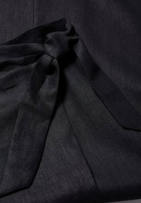 Tissu noir avec un détail de nœud noué, montrant des plis doux et une surface légèrement texturée.