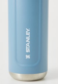 Sticlă de apă din oțel inoxidabil albastru, cu un finisaj mat neted, având logo-ul alb "STANLEY" și o basis metalică argintie.