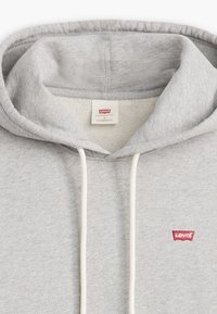 Sudadera gris con un corte estándar, que presenta una capucha con cordón, textura acanalada y una etiqueta del logo rojo de Levi's en el pecho.