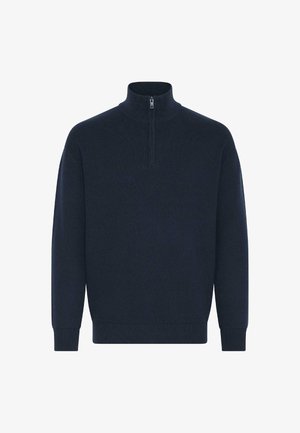 Tumedat sinine sviiter kõrge kraega, millel on pool-luku sulgemine ja soonikud mansettides ning allservas. Pehme tekstuur klassikalise kudumise disainiga.