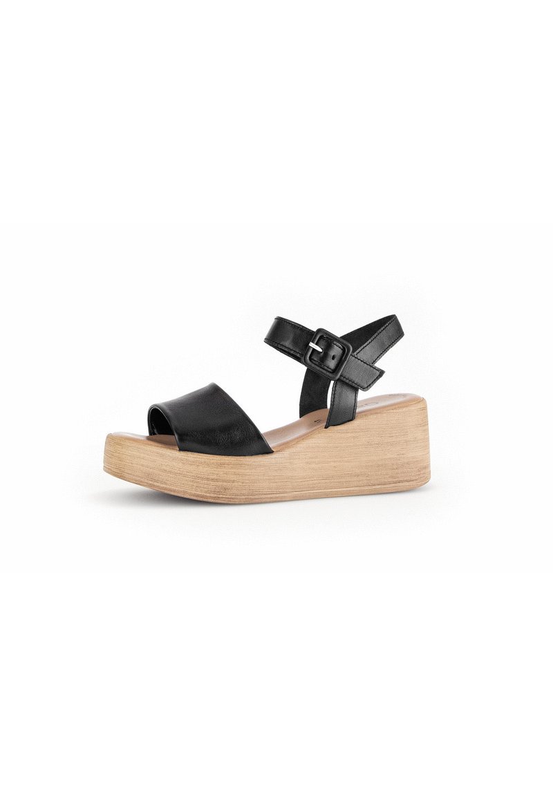 Sandalia de cuña de cuero negro con diseño de punta abierta, correa ajustable en el tobillo y plataforma de madera clara.