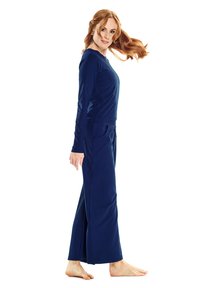 Navyblauw loungewear-set met een langslavende top en wijde broekspijpen, gemaakt van zachte stof met een losse pasvorm en zijzakken.