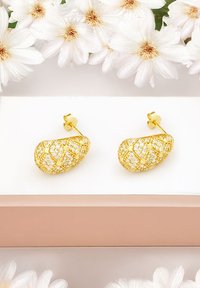 Guldörhängen med en skulptural, tårformad design, med en texturerad yta prydd med klara, glittrande stenar i ett korsmönster.