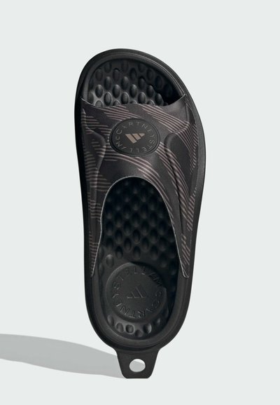 Black slide sandal with a textured, patterned upper, circular logo detail, and a contoured footbed featuring raised dots for grip.