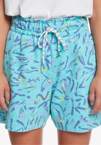 Ljusblå shorts med dragsko i midjan, med ett flerfärgat abstrakt mönster av lila och gula penseldrag. Mjuk textur.