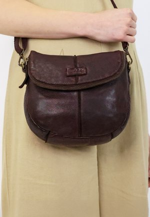 Braune Leder-Crossbody-Tasche in runder Form, mit Reißverschluss und verstellbarem Riemen; verfügt über ein kleines Logo auf der Vorderseite.