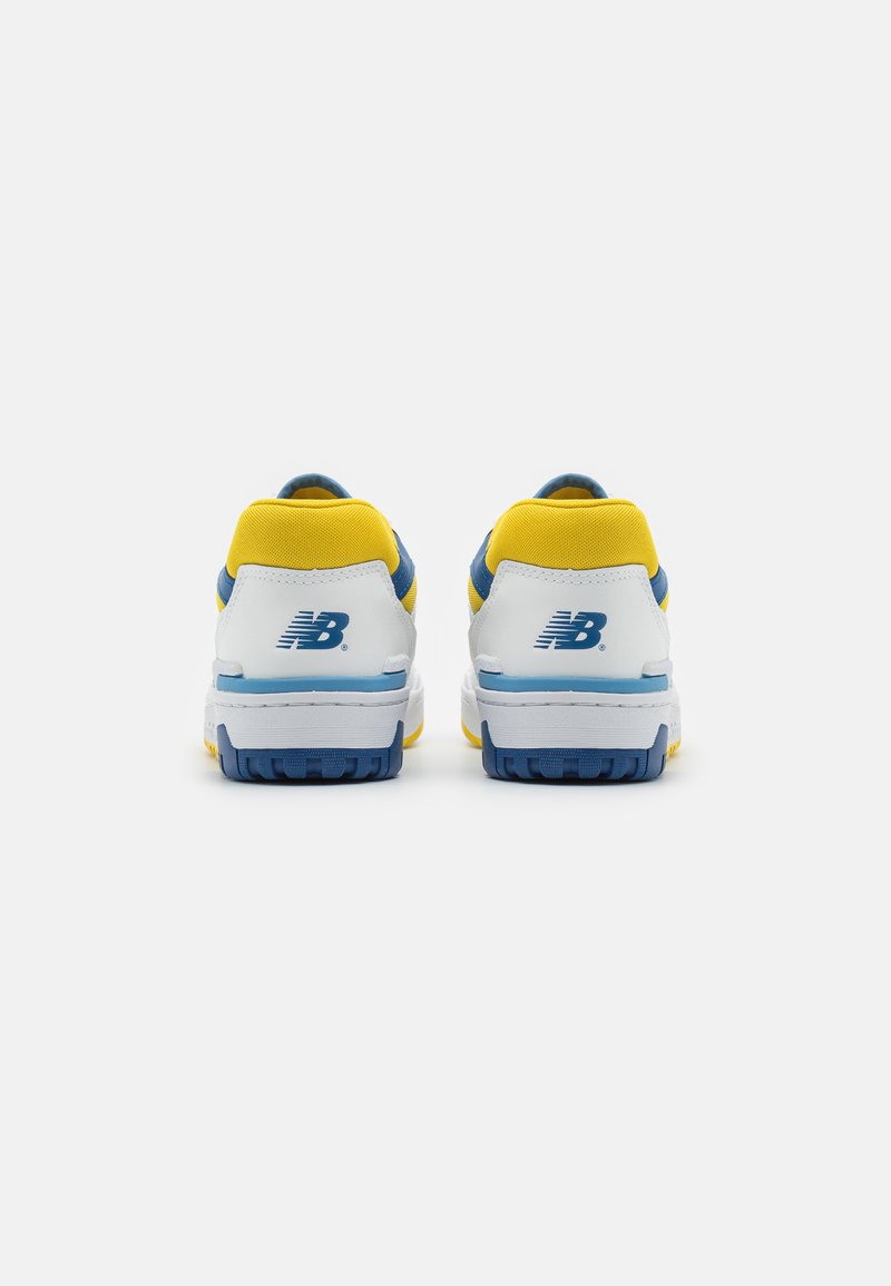 Weiße Sneakers mit gelben und blauen Akzenten, mit einem strukturierten Obermaterial, gepolstertem Kragen und einem markanten Logo an der Ferse.