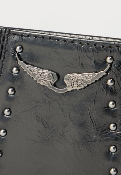 Μαύρο δέρμα με ασημένια διακοσμητικά σε σχήμα φτερών και στρογγυλές ασημένιες καρφίτσες τοποθετημένες σε κάθετες γραμμές.