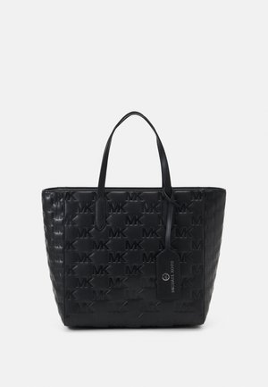 Black tote bag made of textured synthetic material, featuring embossed "MK" logo pattern, dual handles, and hangtag detailing.