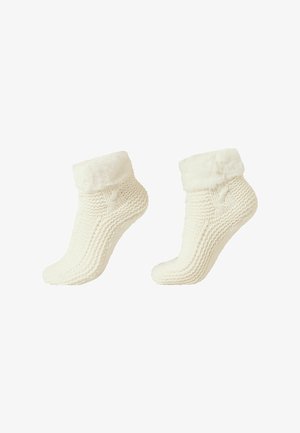 Calcetines de color crema de punto con un puño de piel sintética, que presentan un tejido texturizado y una forma acogedora y curva. Ideales para proporcionar calidez y confort.