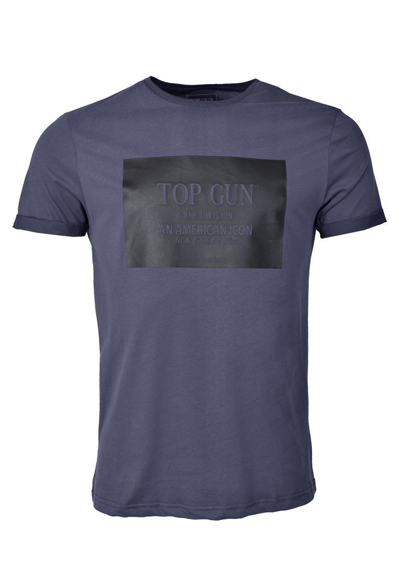 Mörkblå bomulls T-shirt med en svart rektangulär patch som visar "TOP GUN 69TH DIVISION AN AMERICAN ICON" i upphöjd skrift. Korta ärmar.