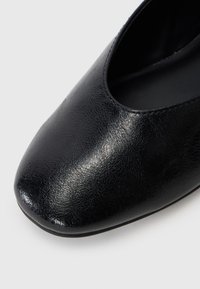 Schwarzer Lederschuh mit glatter Textur, runder Zehenform und einem niedrig ausgeschnittenen Schaftdesign. Die Sohle ist flach und minimalistisch.