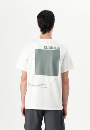 White cotton t-shirt featuring a graphic design of overlapping squares in green on the back, with "CALVIN KLEIN" printed above it.