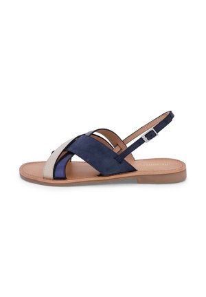 Sandale plate avec semelle beige et brides croisées en marine, bleu foncé et beige, dotée d'une bride de cheville réglable à boucle.