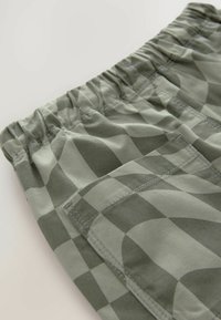 Shorts verts à motifs avec une taille élastique, dotés d'une poche plaquée et d'un tissu lisse et léger au design géométrique.