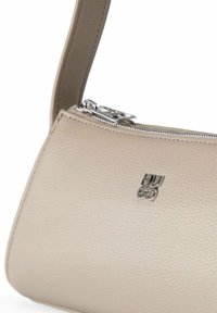 Bolso de cuero beige texturizado con cremallera plateada y logo de Hugo en el frente, mostrando una correa parcial sobre un fondo blanco.