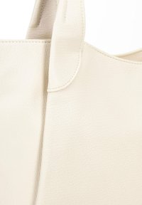 Tote bag van zacht, off-white gestructureerd leer. Beschikt over stevige handvatten en een strak ontwerp zonder zichtbare hardware of versieringen.