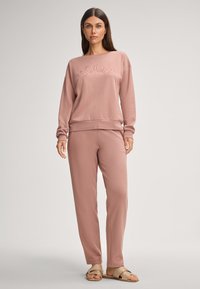 Lichtroze sweatshirt met "JOOP!" geborduurd op de borst, in combinatie met bijpassende lichtroze broek. Zachte textuur, relaxte pasvorm.