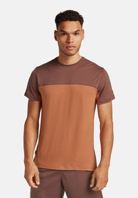 T-shirt a maniche corte con un design a blocchi di colore nelle tonalità di marrone. Realizzato in un tessuto testurizzato, presenta un collo rotondo e dettagli cuciti.