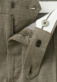 Smeđe karo hlače sa zatvaračem, kopčom i metalnim kukom na bijelom prugastom pojasu.