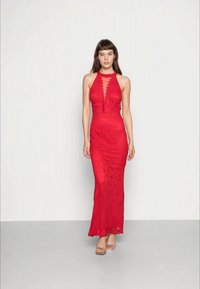 Vestido de renda vermelha com decote halter, detalhes em scallop, corte justo e design até ao chão. Realçado com textura transparente e padrões subtis.