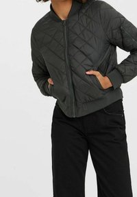 Kurtka bomberka w ciemnozielonym kolorze z pikowaniem, zamkiem błyskawicznym z przodu, ściągaczami na rękawach oraz kieszeniami bocznymi. Gładka faktura i dopasowany fason.