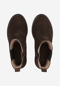 Brown suede ankle boots with a zipper on each side, cream-colored interior, and a flat, textured sole.