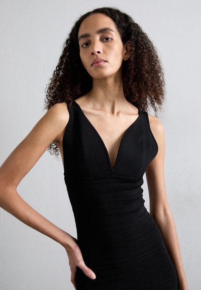 Vestido negro sin mangas con un escote en V profundo, tejido texturizado con rayas horizontales, silueta ajustada y detalles sutiles a lo largo de los bordes.