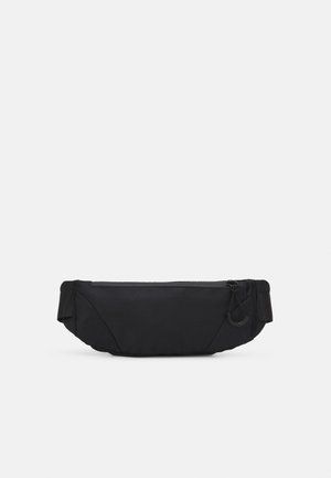 Sac à taille noir en tissu avec une texture lisse, de forme rectangulaire, fermeture par zip central et un détail en boucle sur le côté.
